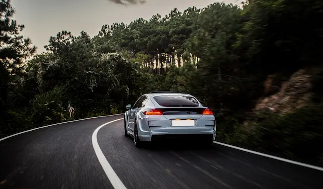 automovil-deportivo-autoajuste-blanco-negro-que-conduce-al-bosque_114579-4076
